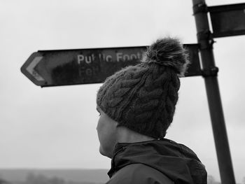 Black and white monochrome side view of a woman next to a sign