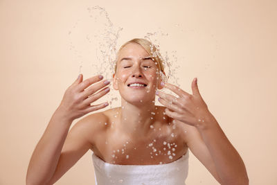 Midsection of woman in water splashing against gray background