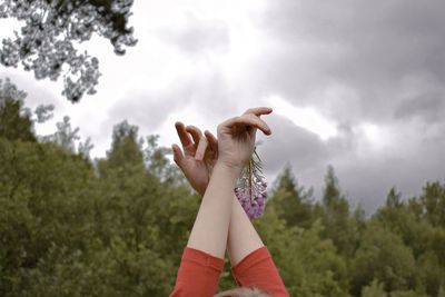 Cropped hands of woman against sky