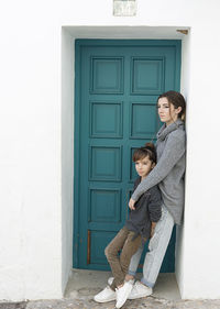 Siblings standing by door of house