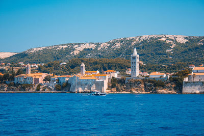 Buildings at waterfront against blue sky