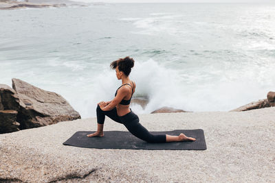 Side view of woman exercising at beach