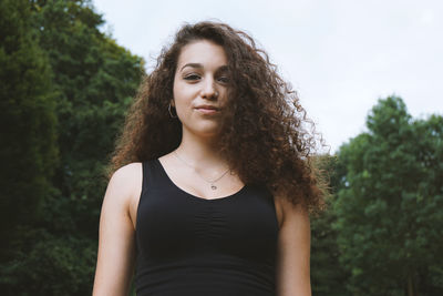 Portrait of young woman standing against trees