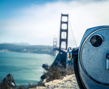 Close-up of coin-operated binoculars on sea shore against sky
