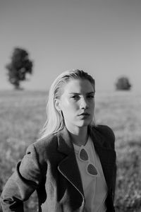 Portrait of a young woman standing in a field during sunset