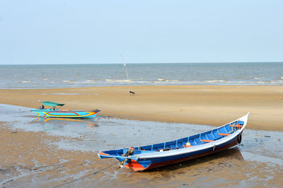 Boat moored on beach against clear sky