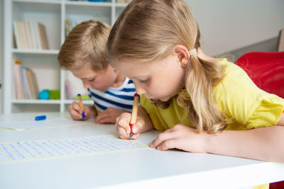 Portrait of boy and girl on table at home