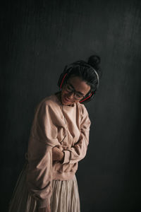 Portrait of young woman standing against black background