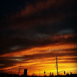 Low angle view of electricity pylon against cloudy sky