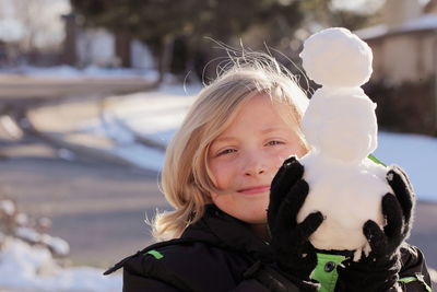 Close-up portrait of smiling girl playing with snow