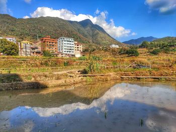 Scenic view of lake by buildings against sky