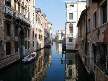 Canal amidst buildings in city against sky