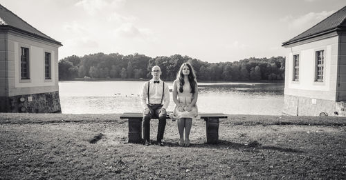 Rear view of people relaxing on bench in front of fountain