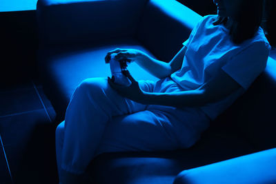 Young woman playing console in neon blue