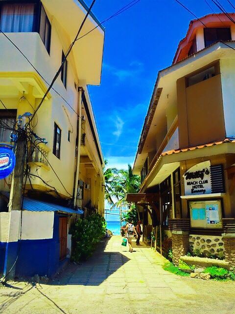 building exterior, architecture, built structure, yellow, residential building, residential structure, house, sky, the way forward, street, transportation, blue, building, city, outdoors, sunlight, town, diminishing perspective, day, no people