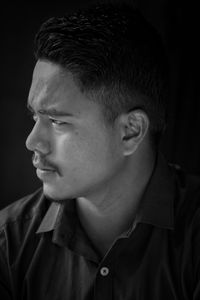 Close-up of man looking away against black background