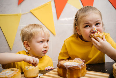 Portrait of two children eating homemade easter sweets indoors