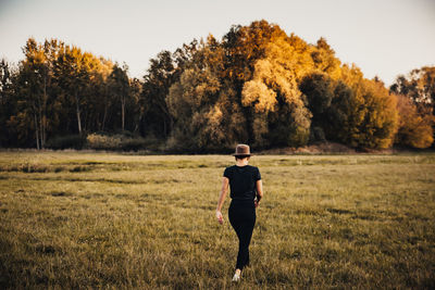 Full length rear view of man walking on field