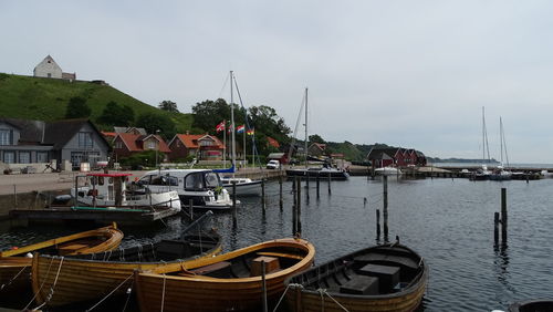 Boats moored at harbor against sky