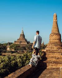 People sitting on temple against clear sky