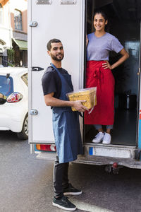 Full length portrait of confident young multi-ethnic colleagues standing at food truck in city