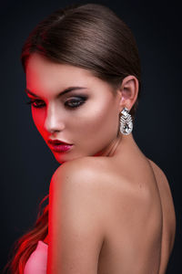 Close-up of young woman against black background