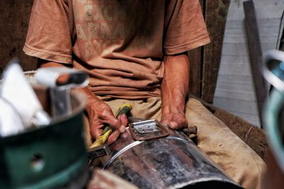 Midsection of man working on metal