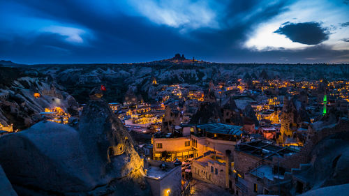 High angle view of illuminated buildings in town against cloudy sky