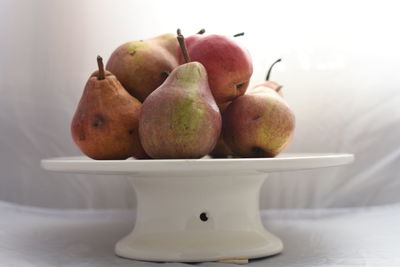 Close-up of pears on cakestand against white background
