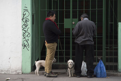 Rear view of people standing with dog