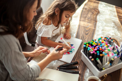 Mother assisting daughter in drawing at home