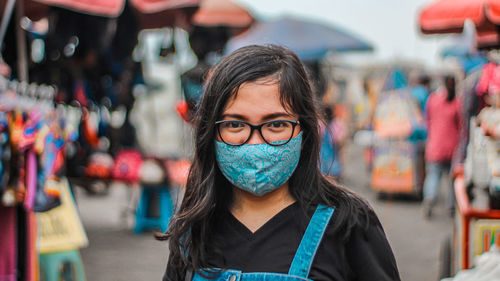 Portrait of young woman wearing mask standing outdoors