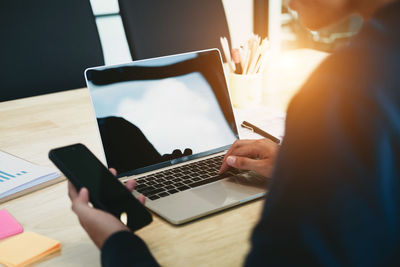 Midsection of man using laptop on table