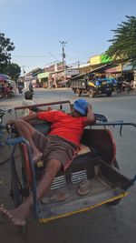 Man lying down on street in city