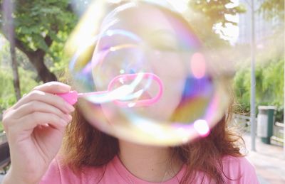 Close-up of woman blowing bubbles on footpath 