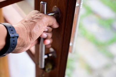 Close-up of man holding cigarette against wooden door