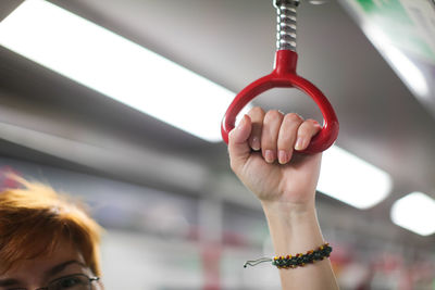 Close-up of woman hand holding red handle in train