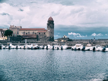 Buildings by river against sky in city