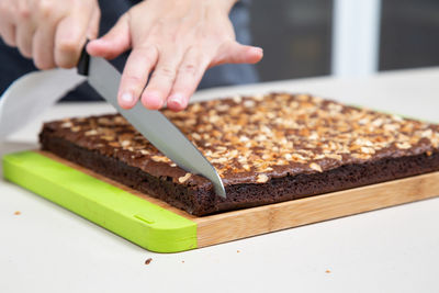 Cropped image of hand holding chocolate cake on table