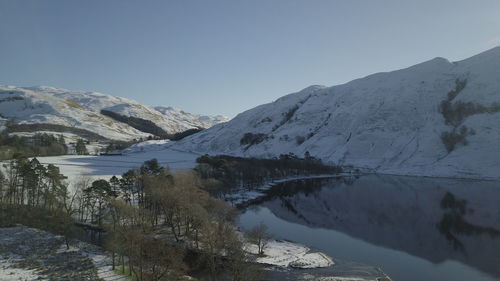 Scenic view of lake and snowcapped mountains against clear sky