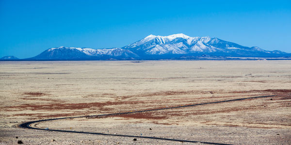 Scenic view of snowcapped mountains against clear blue sky