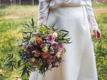 Midsection of person holding bouquet of flowering plant