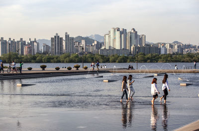 People enjoying at riverfront city water park during sunny day