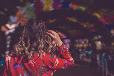 Rear view of woman with umbrella in background