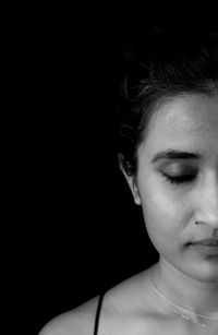 Close-up portrait of young woman against black background