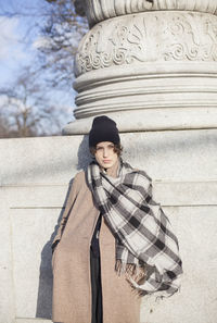 Portrait of woman standing against wall