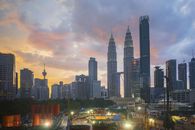 Buildings in city against cloudy sky during sunset