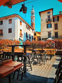 Empty chairs and tables at sidewalk cafe against buildings in city