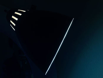 Low angle view of illuminated lighting equipment against black background