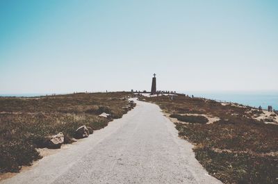 Lighthouse by sea against clear sky